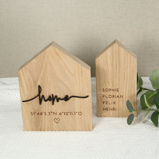 Personalisierte Deko-Häuser aus Holz mit Gravur – links mit Schriftzug „Home“ und Koordinaten, rechts mit Familiennamen  – handgefertigt, natürliche Holzmaserung, liebevolle Geschenkidee zur Hochzeit oder zum Einzug.