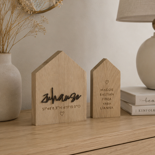 Personalisiertes Deko-Haus aus Holz mit Gravur „Zuhause“ und Koordinaten dekoriert auf einem Sideboard in einem Raum im Scandi Stil