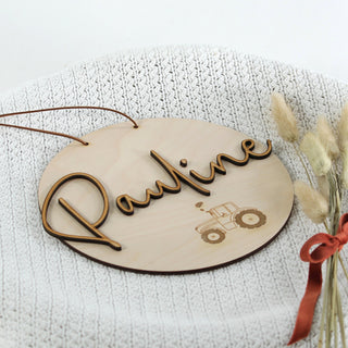 Personalisiertes Holzschild aus hellem Holz mit dem Wunschnamen als 3D-Schriftzug und zartem lasergraviertem Traktor – Detailansicht