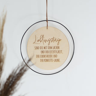 Rundes Holzschild mit schwarzem Metallrahmen und Spruch „Lieblingstage sind die mit dem Lachen…“ – handgefertigte Wanddeko aus Holz, liebevoll gestaltet für besondere Momente.