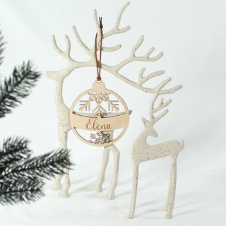 Personalisierte Weihnachtskugel aus Holz mit Schneeflockenmotiv und eingraviertem Namen – handgefertigtes Ornament für den Weihnachtsbaum oder als Geschenkanhänger. Dekoriert an schlichten Hirschfiguren.