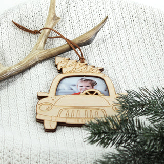Holzornament in Form eines Autos mit Weihnachtsbaum auf dem Dach und einem Fotoeinsatz, in dem ein Kind sitzt – personalisierbarer Weihnachtsschmuck zum Selbstgestalten.