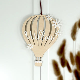 Personalisiertes Holzschild Heißluftballon mit weißem Acryl-Namensschriftzug und kleinen Gänseblümchen als Kinderzimmer Deko