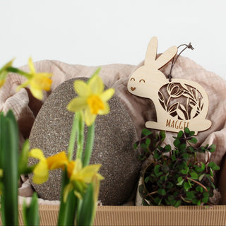 Personalisierter Osteranhänger aus Holz in Hasenform mit filigranem Blumenmuster und Namen. Handgemachte Osterdekoration in einem Osterkörbchen.
