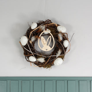 Personalisierter Osteranhänger aus Holz mit Hasenohren im Ei, gelasert mit Namen. Moderne Osterdekoration zum Aufhängen, dekoriert an einem Oster Kranz.